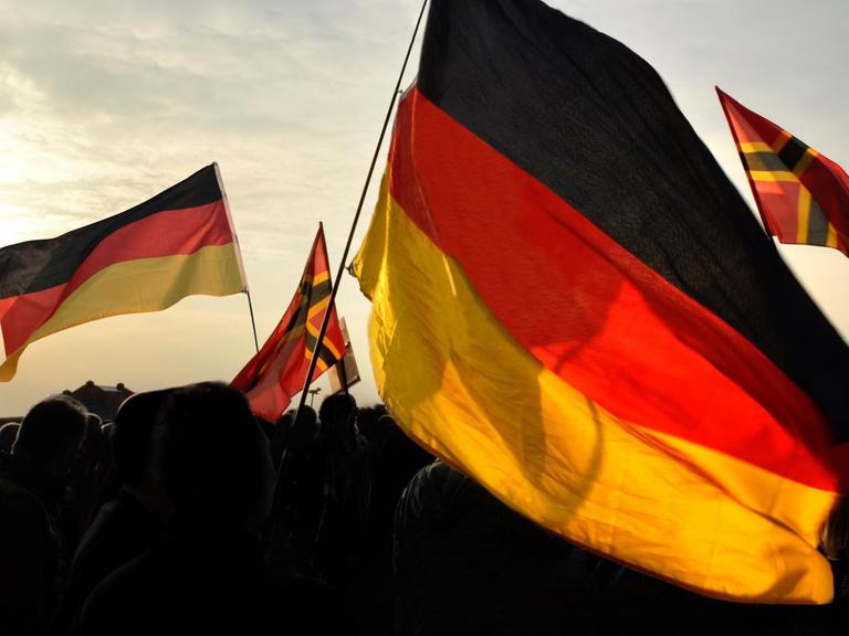 Deutschlandflaggen auf einer Demonstration neben Flaggen der rechten Reichsbürgerbewegung.