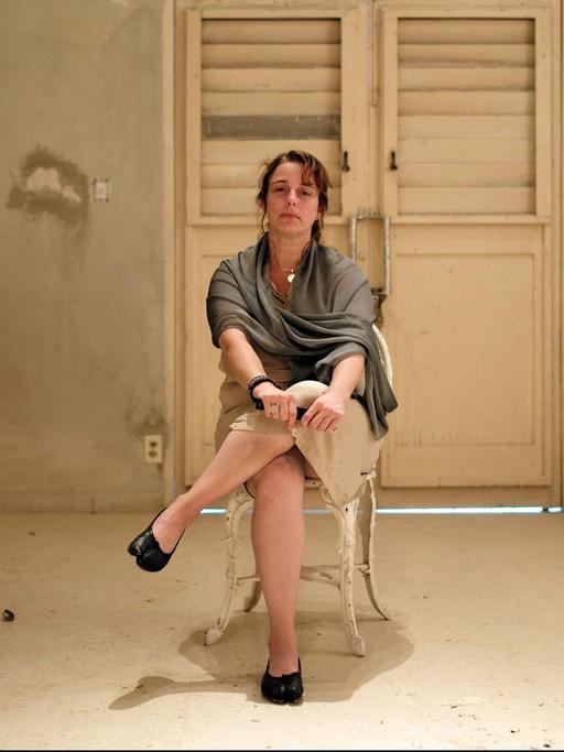 Die kubanische Künstlerin Tania Bruguera sitzt auf einem Stuhl.