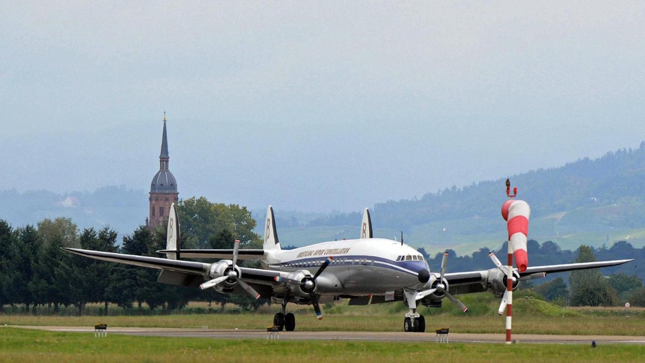 Eine Schweizer Flugzeug steht auf dem Flughafen Lahr im Schwarzwald. Im Hintergrund die Kirche von Schutterzell
