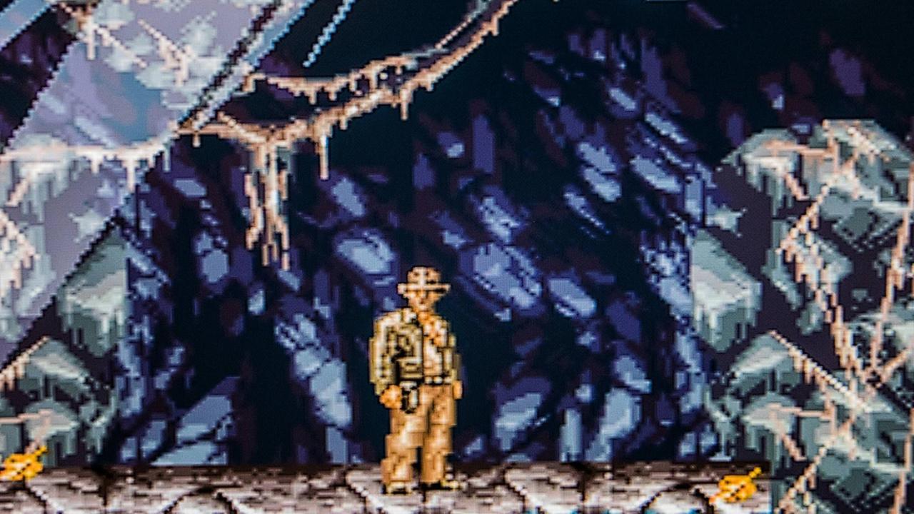 Screenshot des Computerspielklassikers "Indiana Jones' Greatest Adventures". Das stark verpixelte Bild zeigt Indiana Jones in einer Höhle.