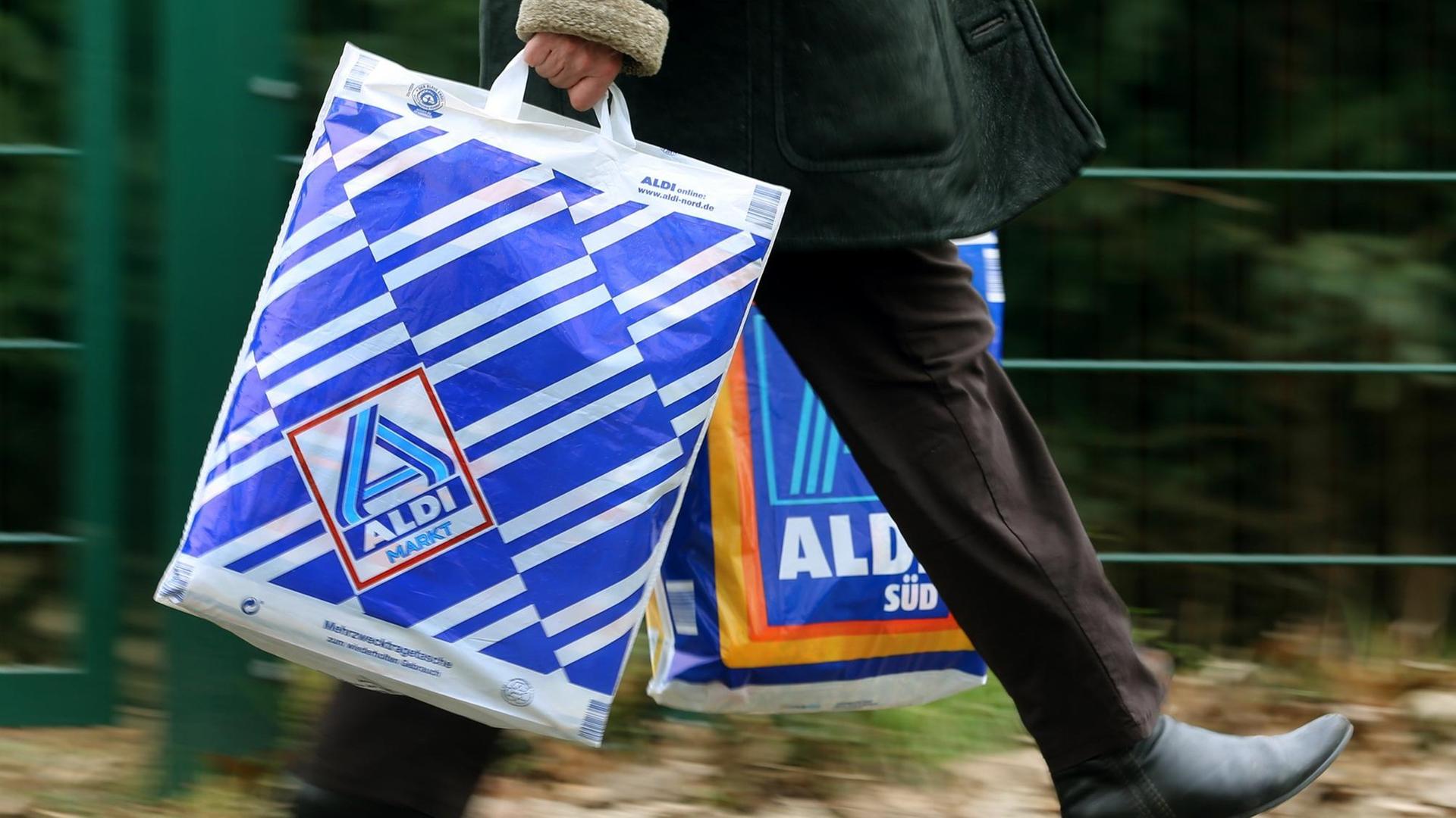 Eine Kundin trägt Einkaufstüten von Aldi-Nord und Aldi-Süd Eine Kundin trägt Einkaufstüten von Aldi-Nord und Aldi-Süd