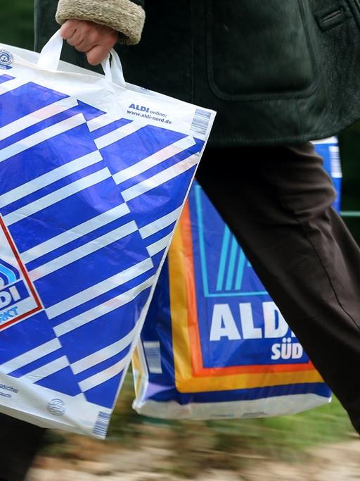 Eine Kundin trägt Einkaufstüten von Aldi-Nord und Aldi-Süd