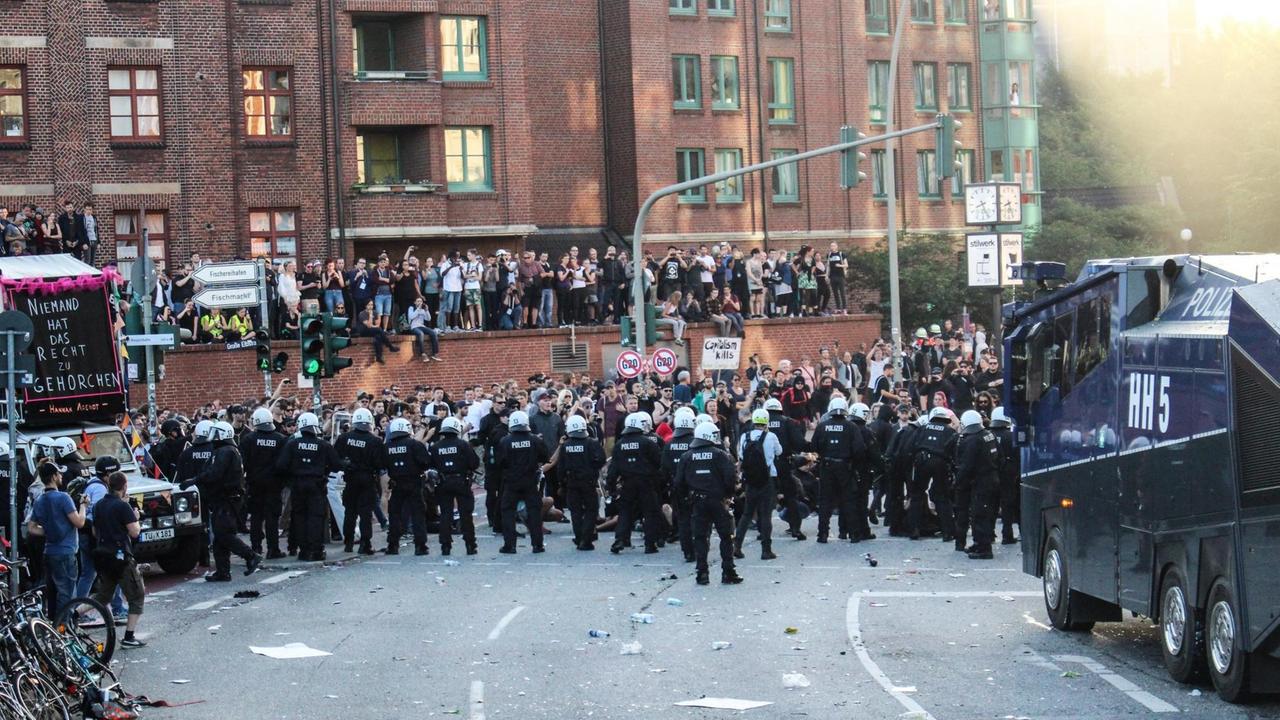Polizeikräfte laufen auf einer Straße in Richtung von Demonstranten. Polizeikräfte laufen auf einer Straße in Richtung von Demonstranten.