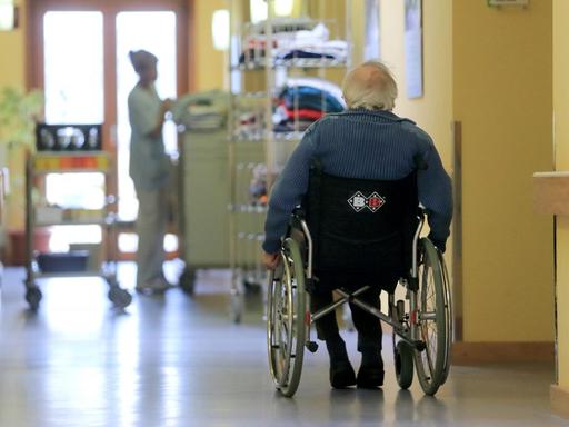 Rentner fährt mit seinem Rollstuhl über einen Flur in einem AWO Seniorenzentrum.