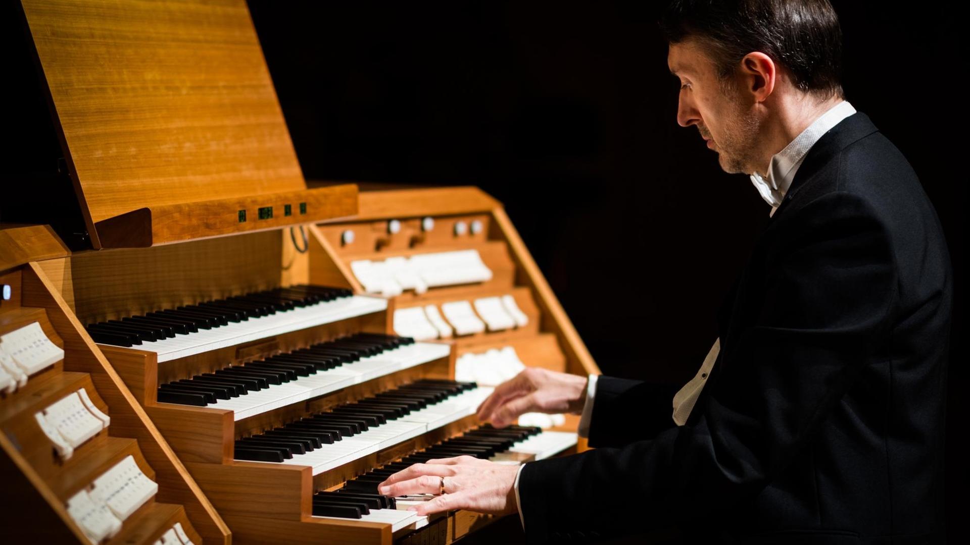 Ein Organist sitzt an einem viermanualigen Orgeltisch.