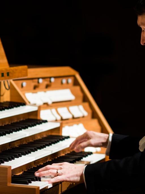 Ein Organist sitzt an einem viermanualigen Orgeltisch.