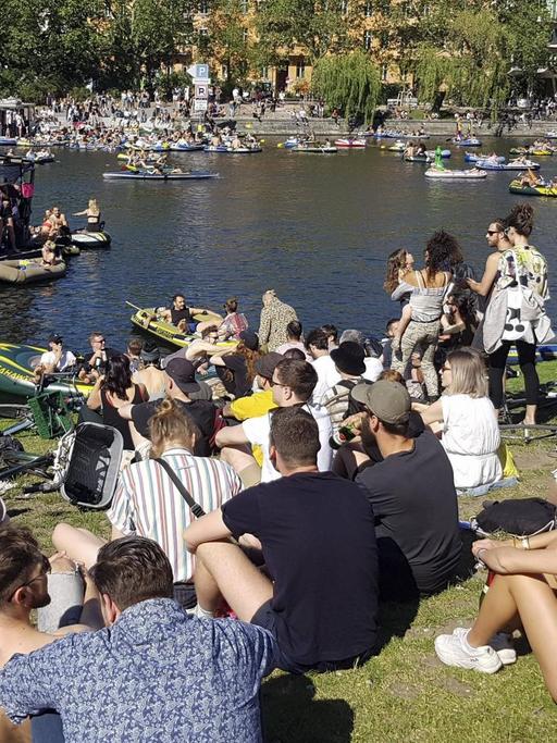 Eine große Menge junger Leute Pfingsten 2020 am Ufer des Berliner Landwehrkanals. Sie sitzen dicht an dicht auf dem Rasen und demonstrieren für Partykultur und Ravekultur.