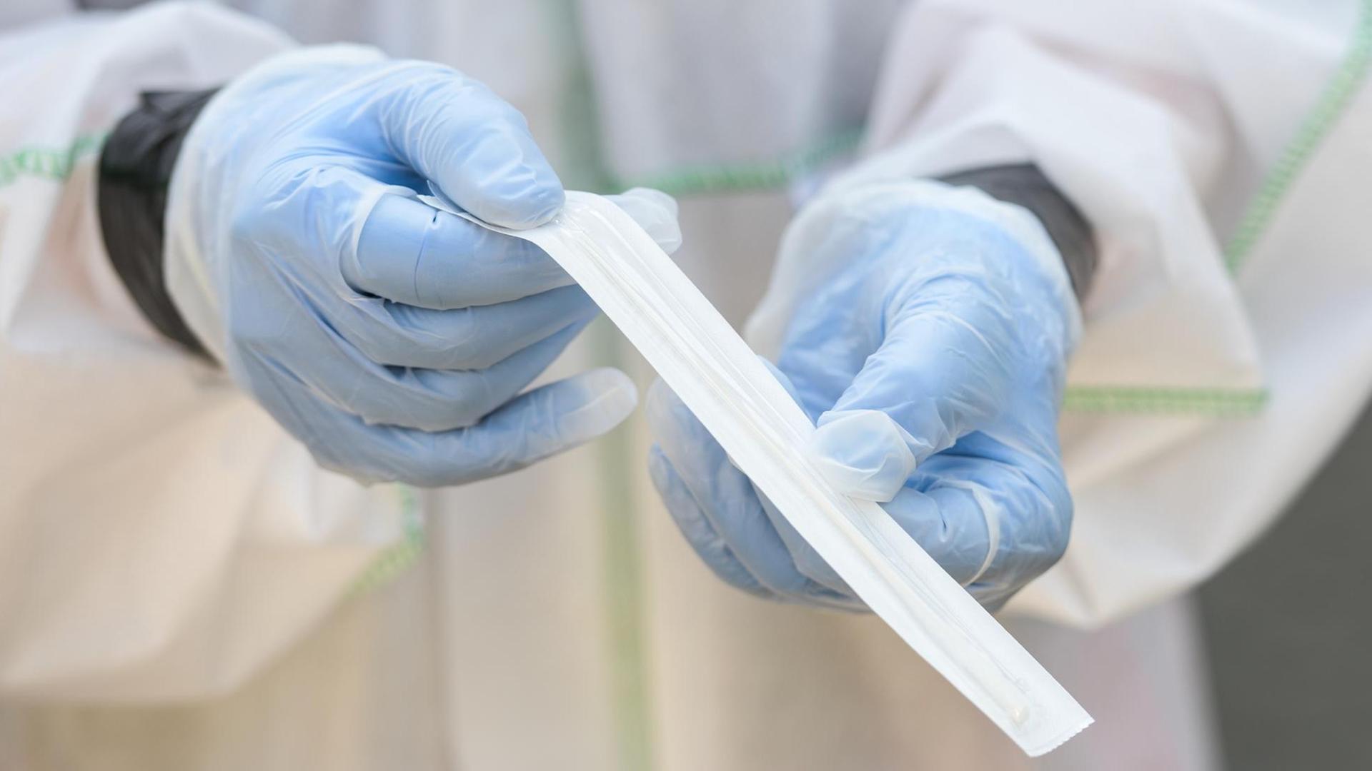 Ein Mitarbeiter des Deutschen Roten Kreuzes hält ein Coronavirus-Teststäbchen für die Speichelprobe. Ein Mitarbeiter des Deutschen Roten Kreuzes hält ein Coronavirus-Teststäbchen für die Speichelprobe.