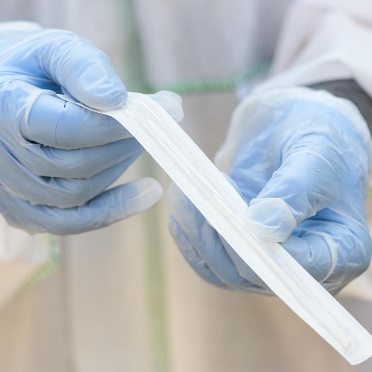 Ein Mitarbeiter des Deutschen Roten Kreuzes hält ein Coronavirus-Teststäbchen für die Speichelprobe. 