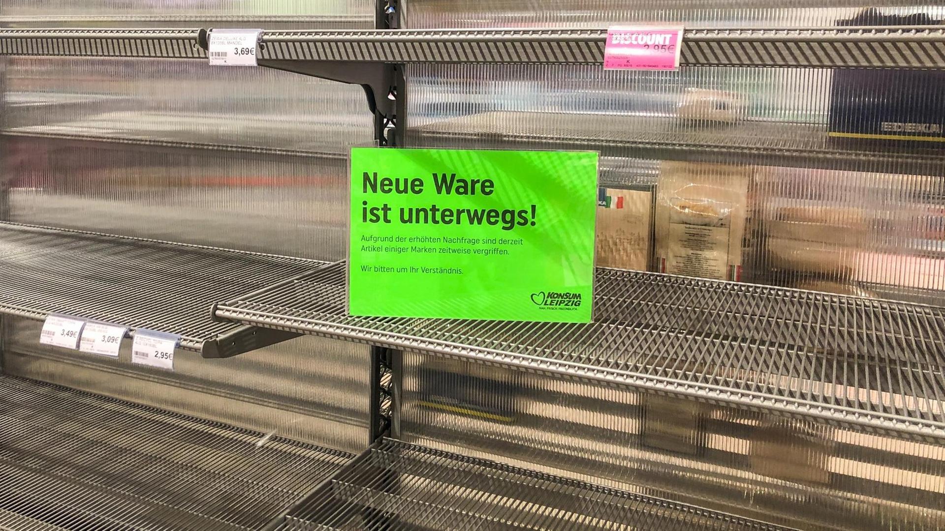 Ein Schild mit der Aufschrift "Neue Ware ist unterwegs!" ist an einem leeren Supermarkt-Regal angebracht, in dem ursprünglich Toilettenpapier stand. Ein Schild mit der Aufschrift "Neue Ware ist unterwegs!" ist an einem leeren Supermarkt-Regal angebracht, in dem ursprünglich Toilettenpapier stand.