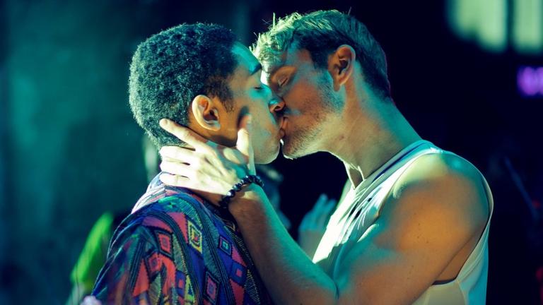 Zwei Männer küssen sich in einem Club. Es sind zwei der Hauptfiguren aus der Serie "Allyou need".