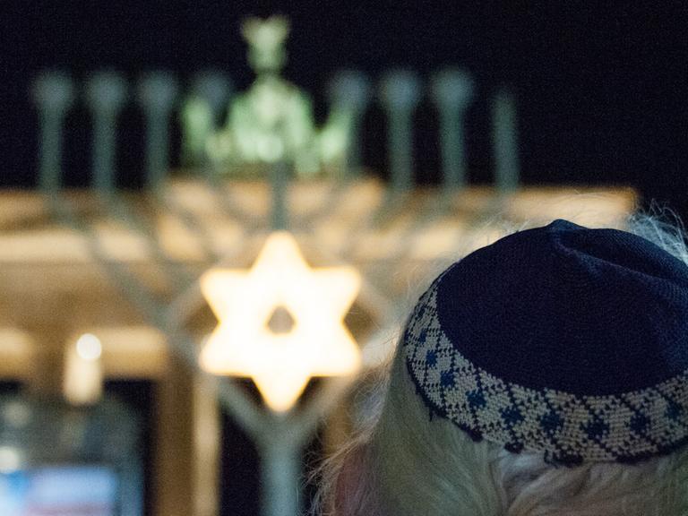 Ein Mann mit Kippa steht am 16. Dezember 2014 in Berlin vor dem Brandenburger Tor. Hier wurde am Abend der Chanukka-Leuchter entzündet.