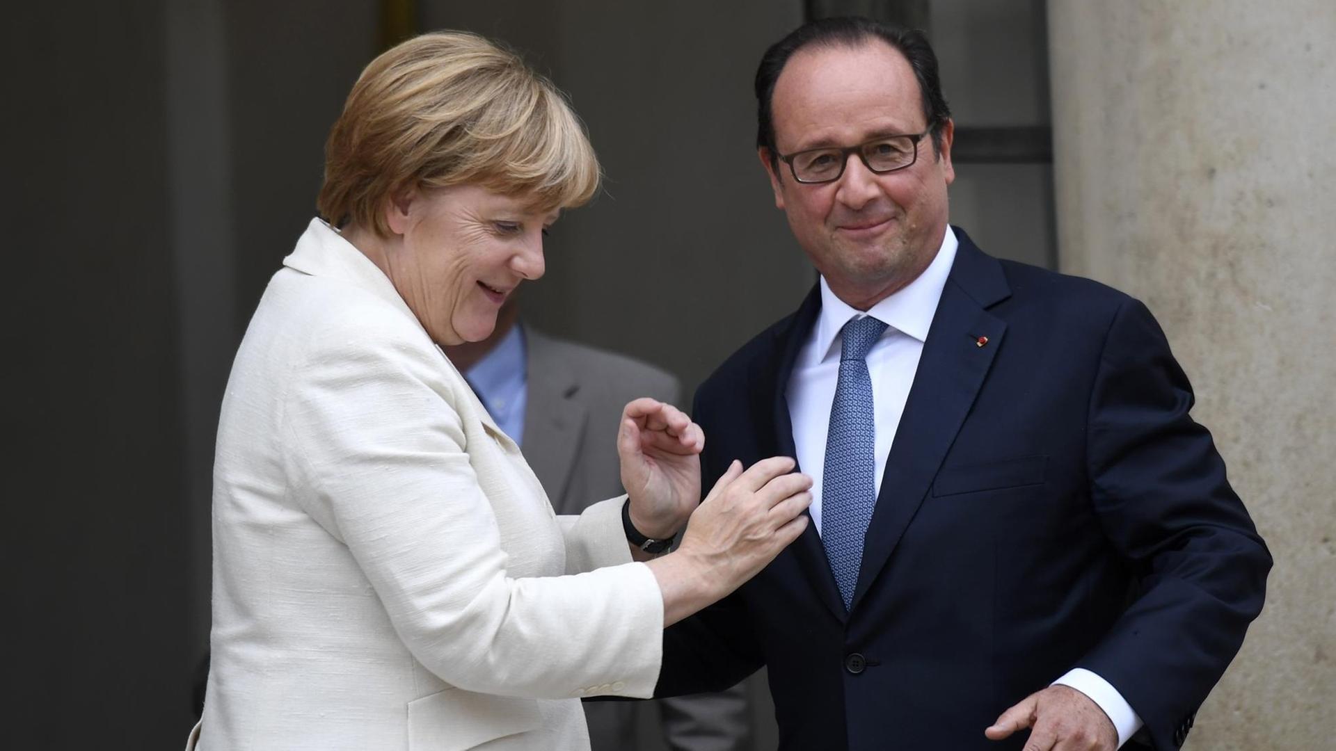 Bundeskanzlerin Merkel und Frankreichs Präsident Hollande stehen nach einem Treffen vor dem Elysee-Palast und wirken vertraut