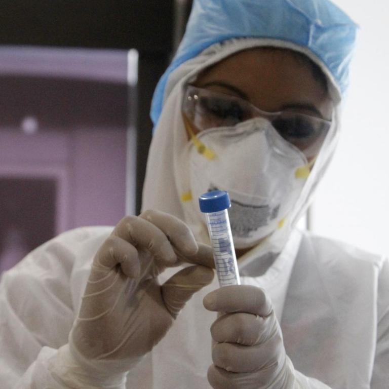 Biologin mit Schutzkleidung bei einem COVID-19-Test im Labor