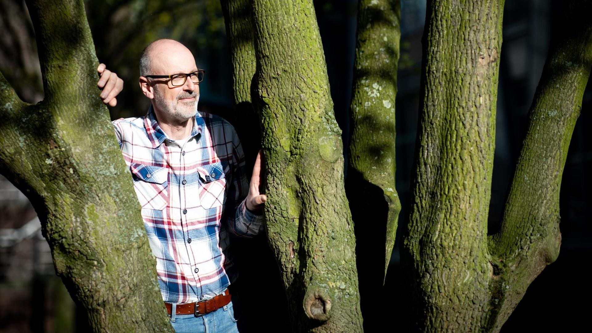 Das Foto zeigt den Förster und Bestseller-Autor Peter Wohlleben, wie er zwischen zwei Bäumen steht. Das Foto zeigt den Förster und Bestseller-Autor Peter Wohlleben, wie er zwischen zwei Bäumen steht.