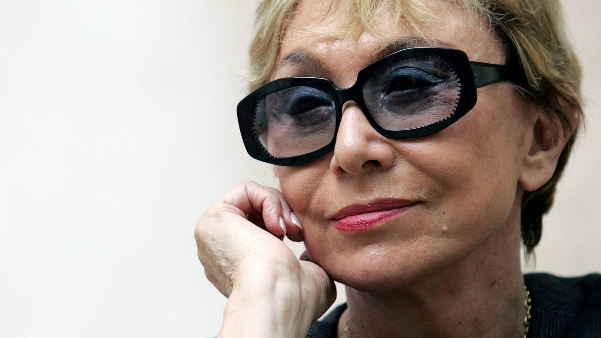 Die Schriftstellerin und Literaturwissenschaftlerin Julia Kristeva ist im Portrait zu sehen mit einer großen, schwarzen Sonnenbrille. Ihre rechte Hand fasst an ihr rechtes Ohr. Die Schriftstellerin und Literaturwissenschaftlerin Julia Kristeva ist im Portrait zu sehen mit einer großen, schwarzen Sonnenbrille. Ihre rechte Hand fasst an ihr rechtes Ohr.