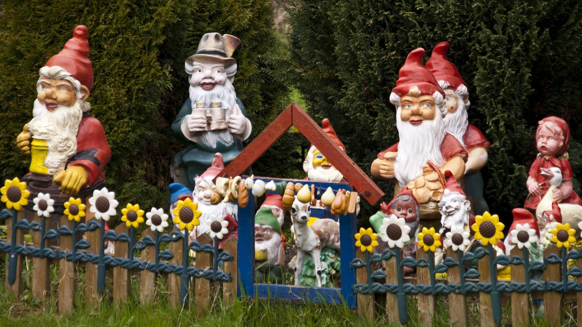 Gartenzwerge aufgereiht hinter einem niedrigen Gartenzaun Gartenzwerge aufgereiht hinter einem niedrigen Gartenzaun