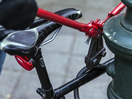Fahrraddiebstahl: Ein Bolzenschneider knackt ein Fahradschloss von einem Rad, dass an einer Laterne steht.