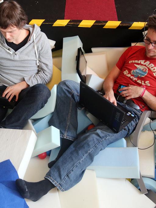 Zwei Männer tippen auf ihren Laptops.