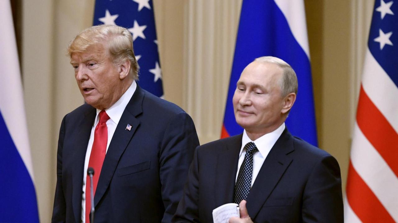 Trump sagt etwas, Putin steht lächelnd daneben. Vor ihnen ein Schild mit der Aufschrift "Helsinki 2018", hinter ihnen die Fahnen beider Staaten. Trump sagt etwas, Putin steht lächelnd daneben. Vor ihnen ein Schild mit der Aufschrift "Helsinki 2018", hinter ihnen die Fahnen beider Staaten.