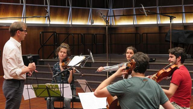 Die Musiker des Aris Quartett sitzen mit ihren Streichinstrumenten in der Hand im Halbkreis zwischen Mikrofonen im Deutschlandfunk Kammermusiksaal und werden von Moderator Christoph Schmitz interviewt.