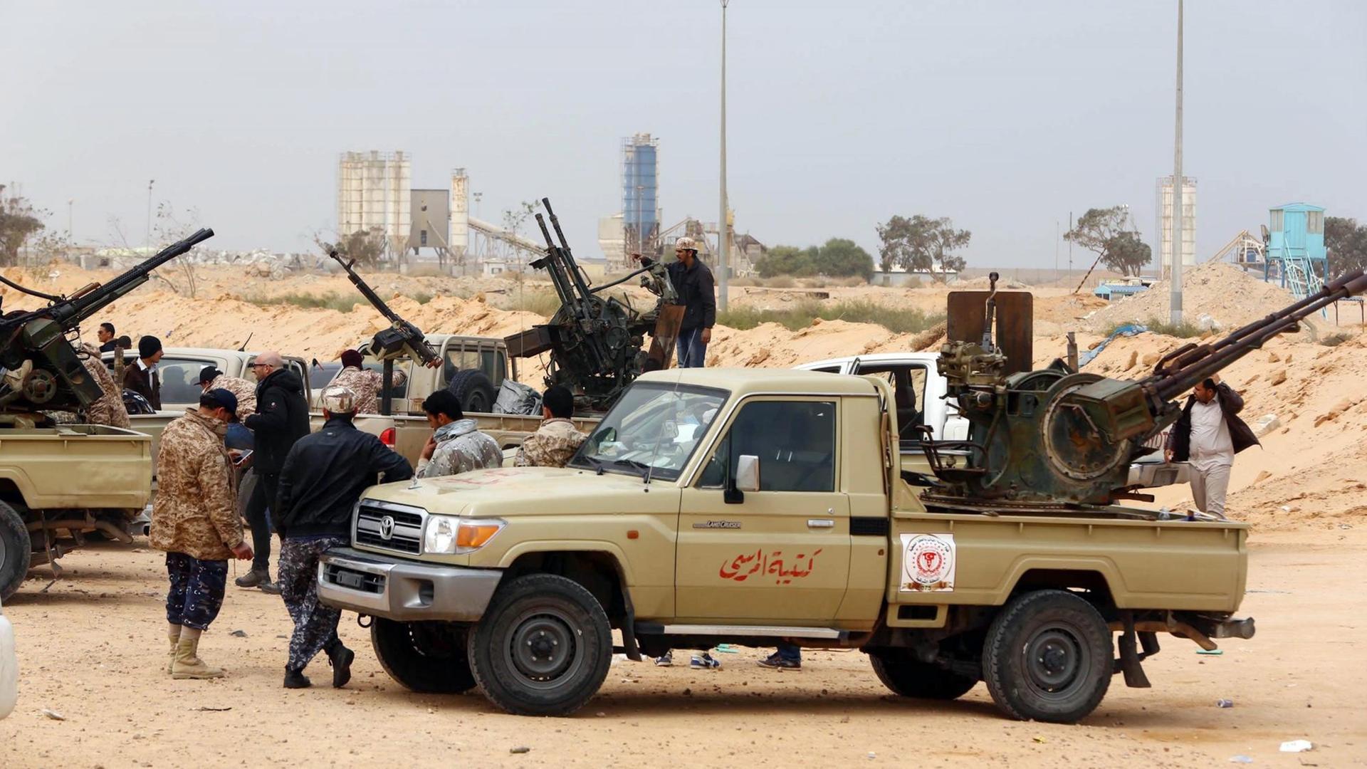 Kämpfer sitzen in der Nähe von Sirte auf Autos, die mit Waffen beladen sind. Kämpfer sitzen in der Nähe von Sirte auf Autos, die mit Waffen beladen sind.