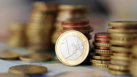 Eine 1-Euro-Münze lehnt am 04.11.2014 in München (Bayern) an gestapelten Münzen.