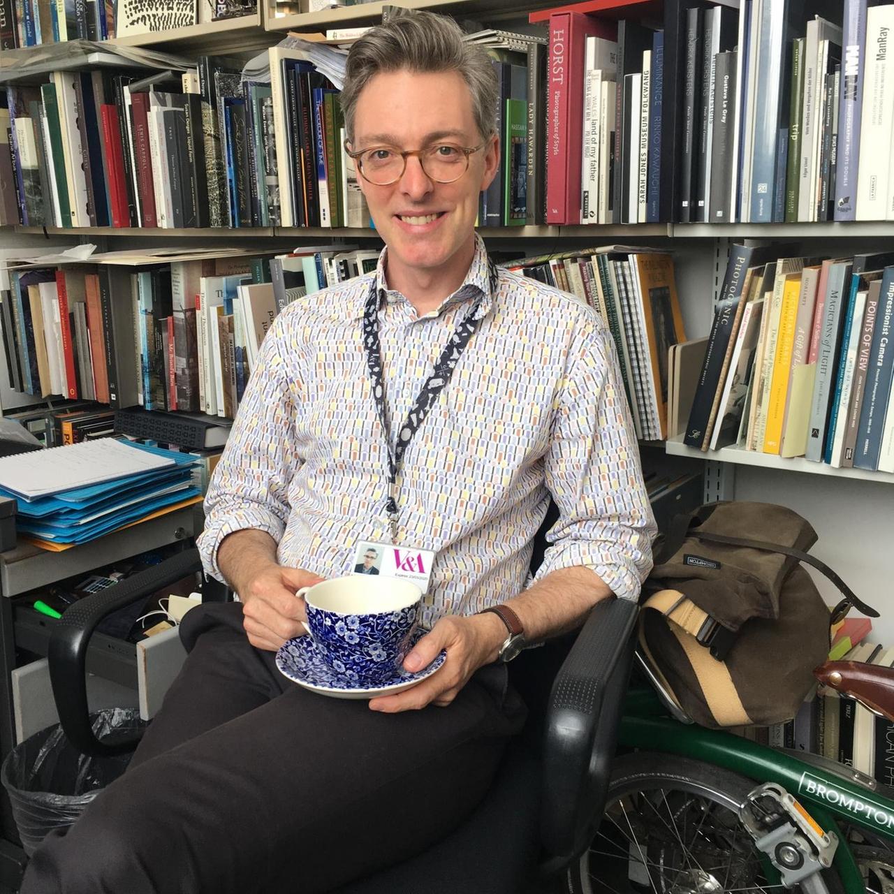 Martin Barnes, Kurator des Fotografiezentrums am Victoria and Albert Museum, sitzt vor seiner Bücherwand im Büro