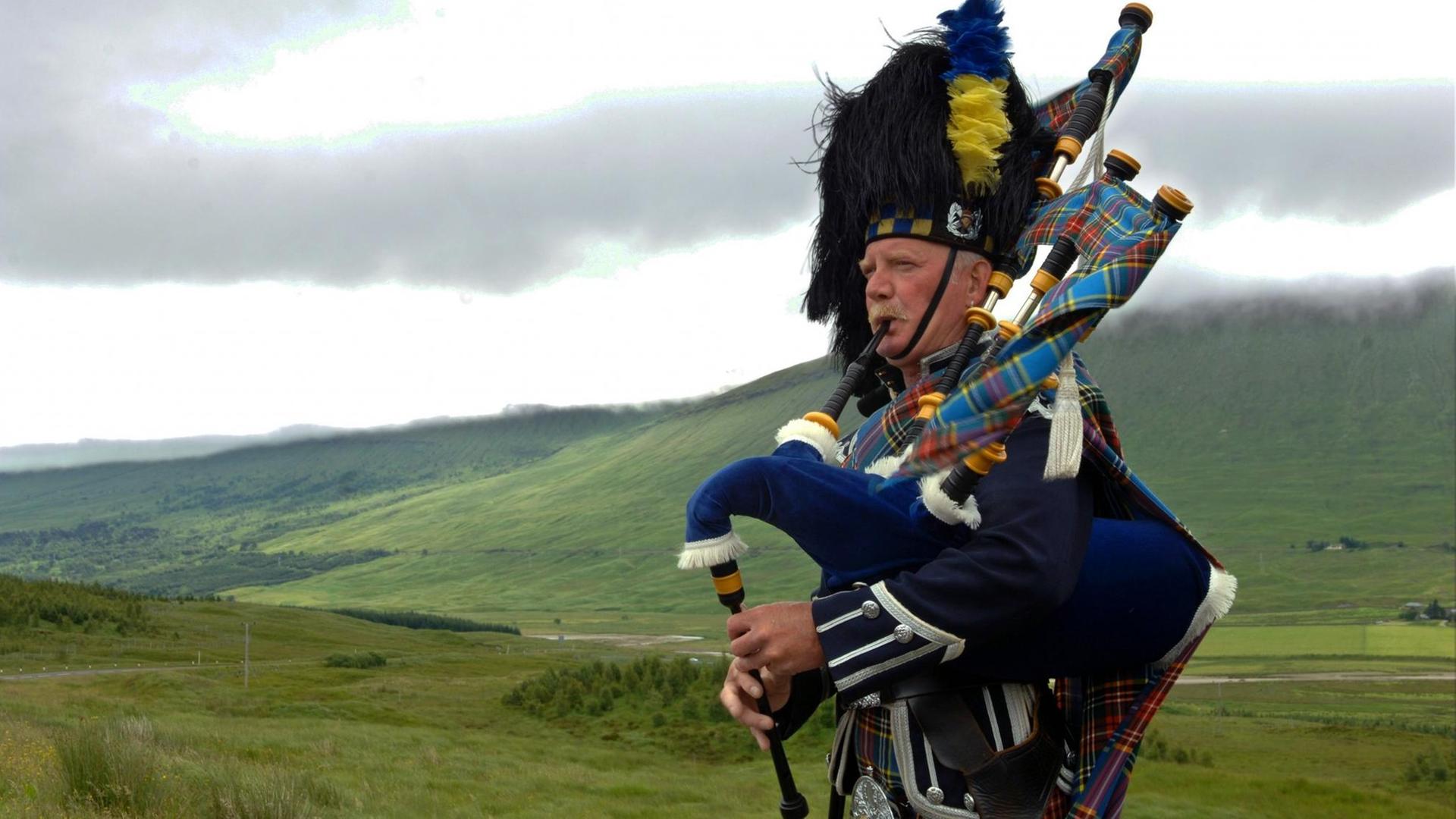 Ein Dudelsackspieler in den Farben des Clans MacBeth spielt im Hochland bei Glen Coe in Schottland für die Touristen, aufgenommen am 09.07.2005. Ein Dudelsackspieler in den Farben des Clans MacBeth spielt im Hochland bei Glen Coe in Schottland für die Touristen, aufgenommen am 09.07.2005.