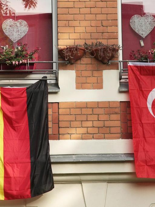 Eine deutsche und eine türkische Fahne hängen in Berlin nebeneinander aus zwei Fenstern einer Wohnung.