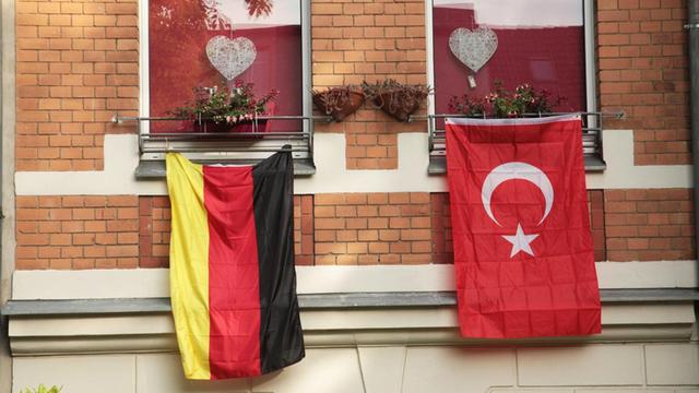Eine deutsche und eine türkische Fahne hängen in Berlin nebeneinander aus zwei Fenstern einer Wohnung.