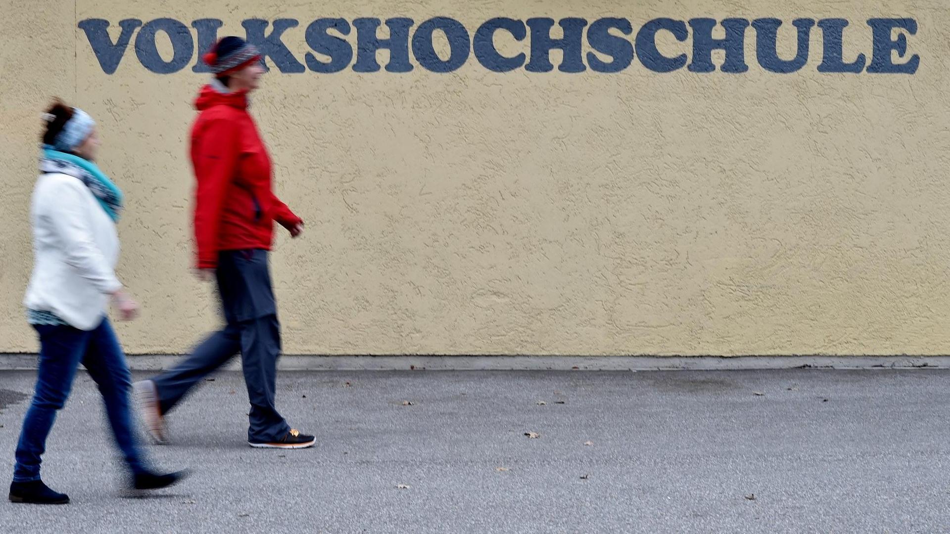 Zwei Frauen gehen in Garmisch-Partenkirchen (Bayern) an einem Schriftzug der Volkshochschule (VHS) vorbei