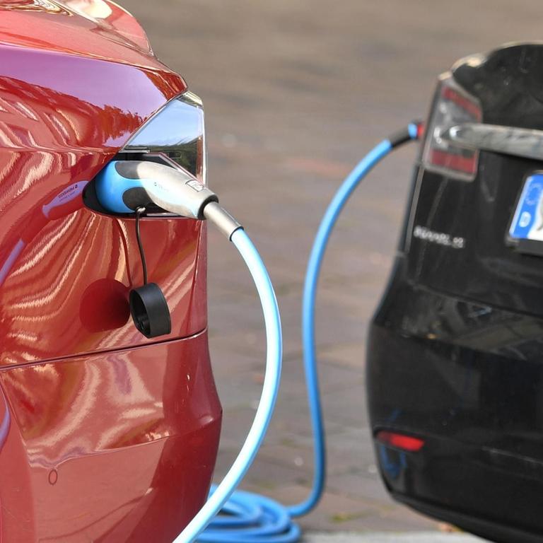 Zwei E-Autos werden an Ladesäulen in aufgeladen. 