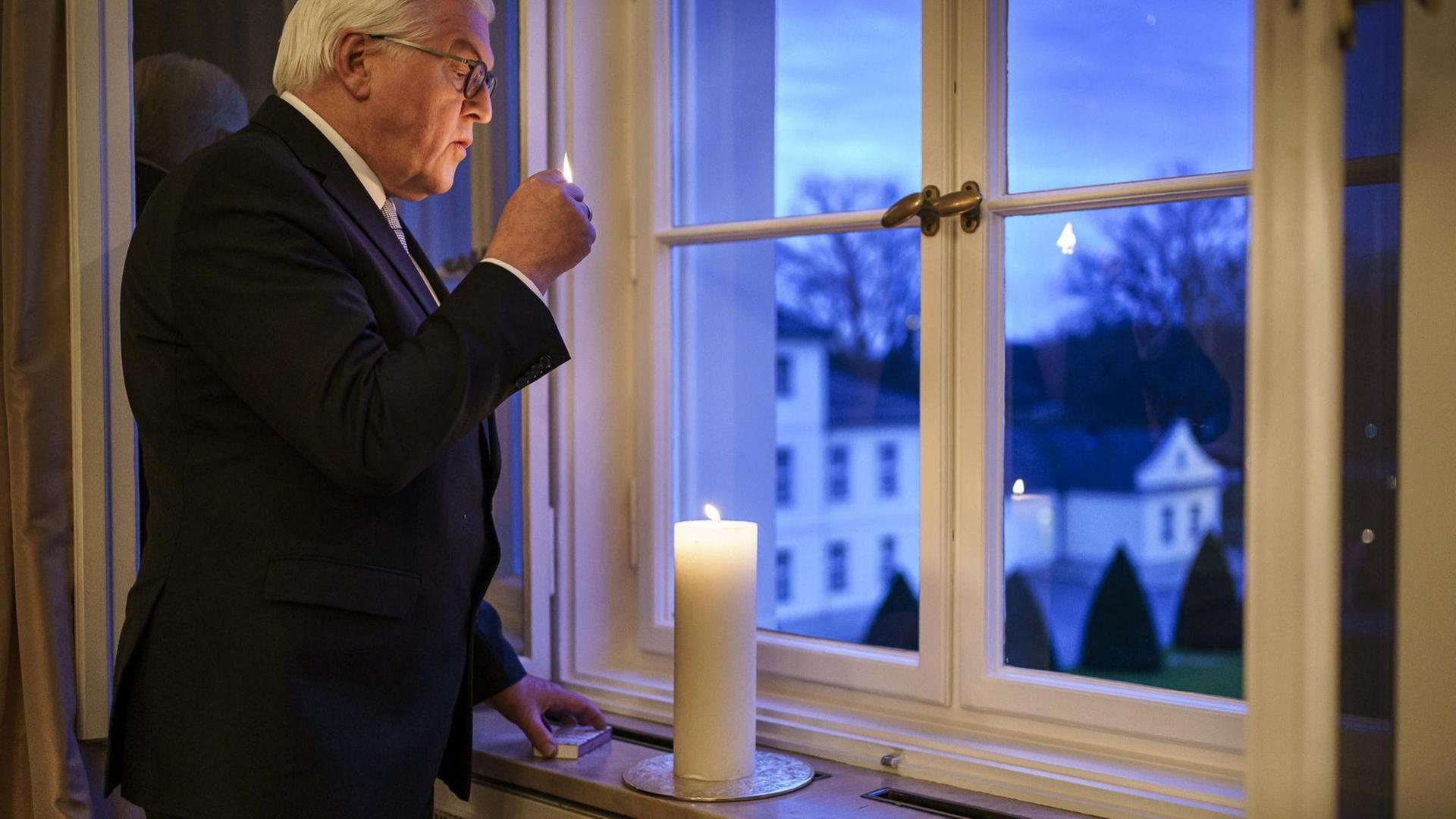 Bundespräsident Frank-Walter Steinmeier zündet eine Kerze vor einem Fenster an Bundespräsident Frank-Walter Steinmeier zündet eine Kerze vor einem Fenster an