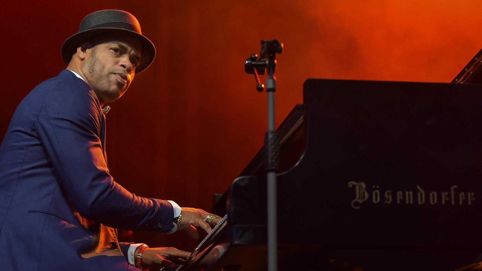 Roberto Fonseca in Anzug und Hut am Klavier. Roberto Fonseca in Anzug und Hut am Klavier.