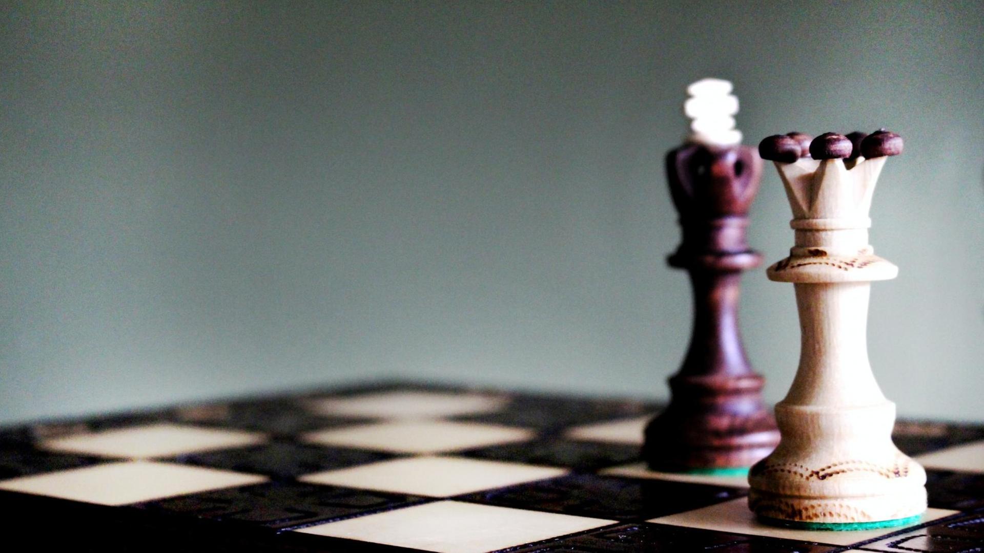Auf einem Schachbrett steht die Spielfigur der Königin im Vordergrund. Auf einem Schachbrett steht die Spielfigur der Königin im Vordergrund.
