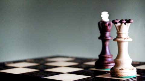 Auf einem Schachbrett steht die Spielfigur der Königin im Vordergrund.