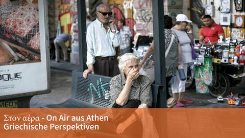 Eine Seniorin wartet an einer Bushaltestelle in Athen.