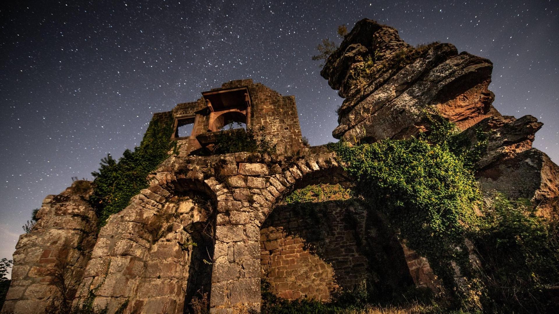 Blick von unten auf eine Ruine mit Sternenhimmel