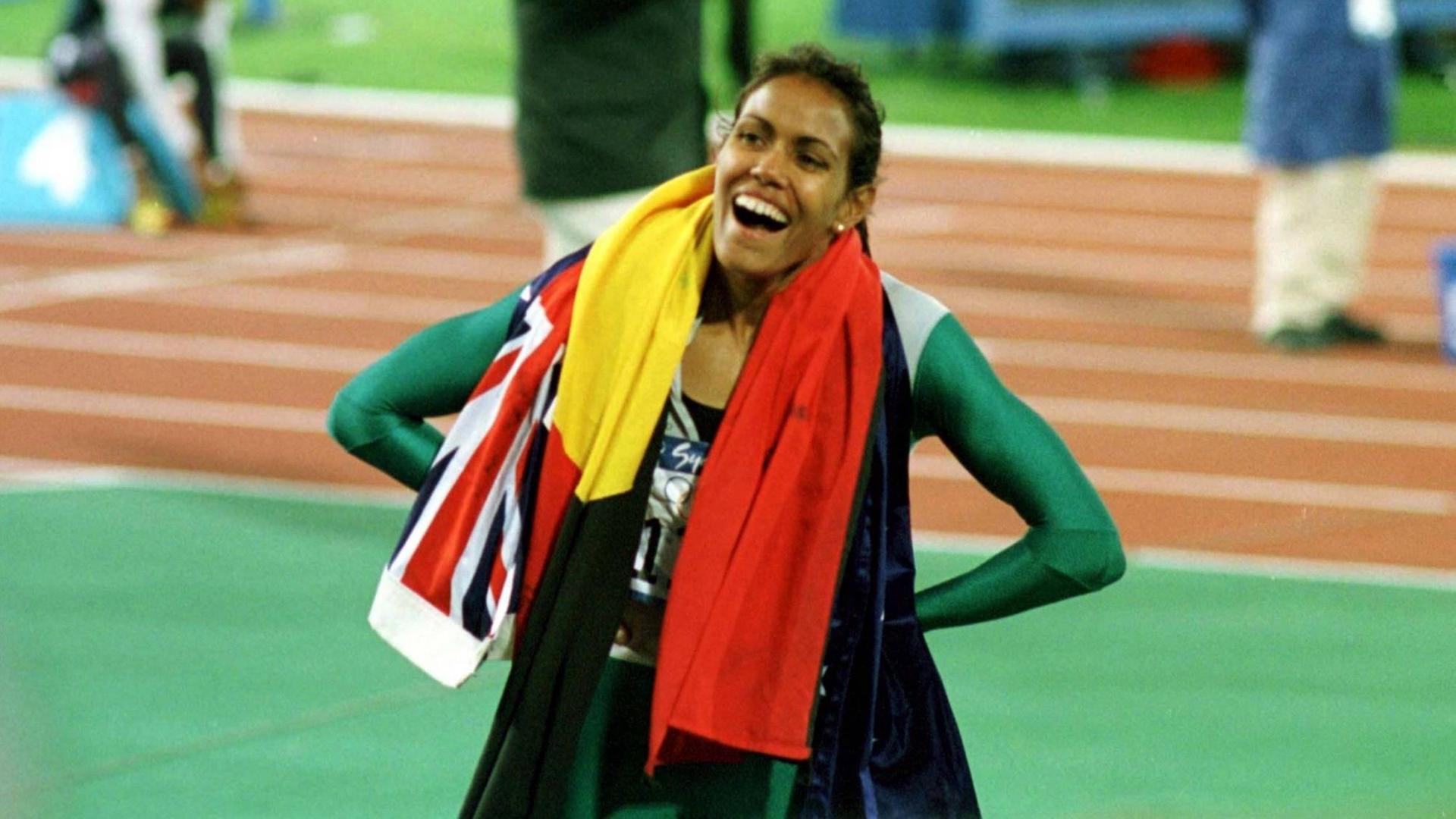 Cathy Freeman in ihrem Rennanzug, hat die Hände in den Hüften und lacht. Cathy Freeman in ihrem Rennanzug, hat die Hände in den Hüften und lacht.