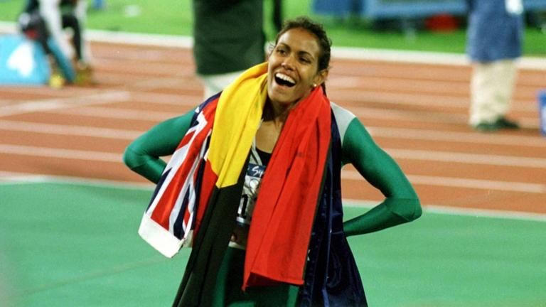 Cathy Freeman in ihrem Rennanzug, hat die Hände in den Hüften und lacht. Cathy Freeman in ihrem Rennanzug, hat die Hände in den Hüften und lacht.
