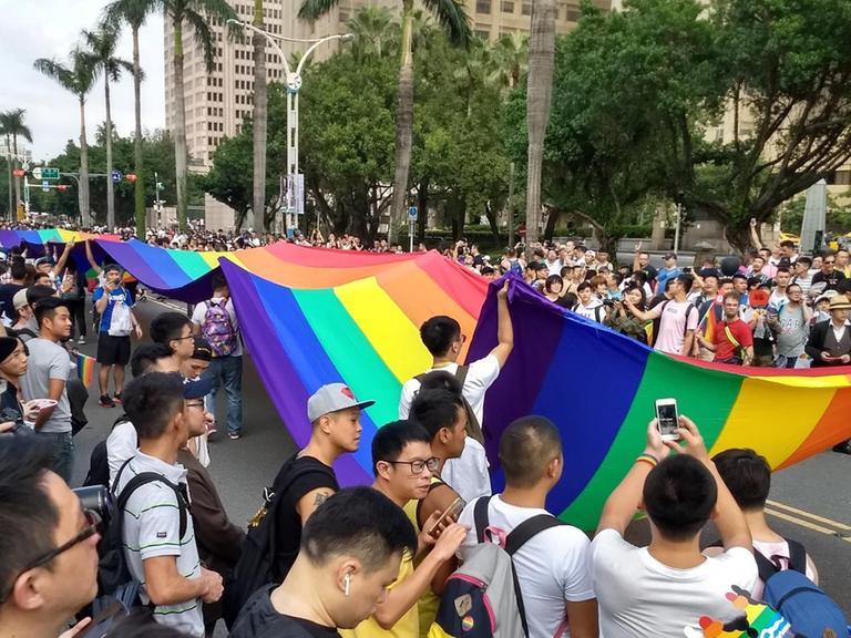 Vor allem männliche Teilnehmer der Gay Pride in Taipeh im Oktober 2017 tragen eine Regenbogenflagge durch die Straße.