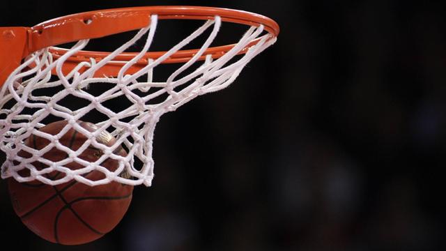 Ein Basketball fliegt in einen Korb.