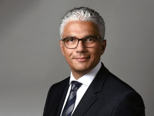 Ein Portrait des Oberbürgermeisters von Bonn, Ashok-Alexander Sridharan. Er trägt einen Anzug und lächelt in die Kamera.
