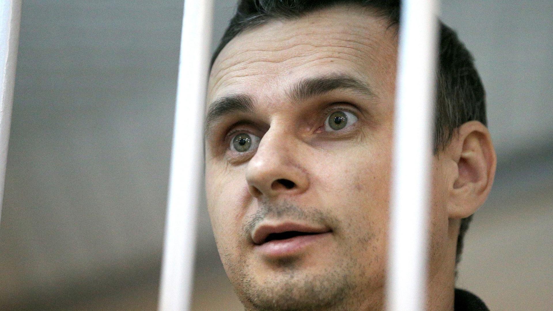 Der ukrainische Kinoregisseur Oleg Senzow wurde von einem russischen Gericht zu 20 Jahren Haft verurteilt; die Aufnahme zeigt ihn bei einer gerichtlichen Anhörung im Dezember 2014 in Moskau in einem Käfig. Der ukrainische Kinoregisseur Oleg Senzow wurde von einem russischen Gericht zu 20 Jahren Haft verurteilt; die Aufnahme zeigt ihn bei einer gerichtlichen Anhörung im Dezember 2014 in Moskau in einem Käfig.