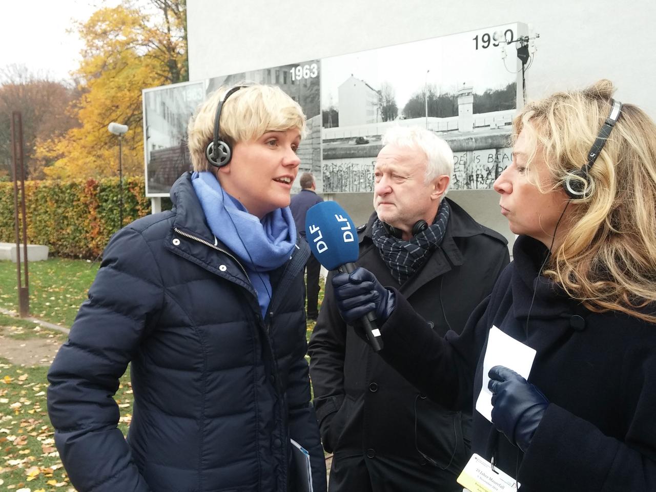 DLF-Redakteurin Bettina Klein im Interview mit Susanne Muhle, Mitkuratorin der Ausstellung "Stiftung Berliner Mauer". Im Hintergrund steht Grünen-Politiker Werner Schulz DLF-Redakteurin Bettina Klein im Interview mit Susanne Muhle, Mitkuratorin der Ausstellung "Stiftung Berliner Mauer". Im Hintergrund steht Grünen-Politiker Werner Schulz