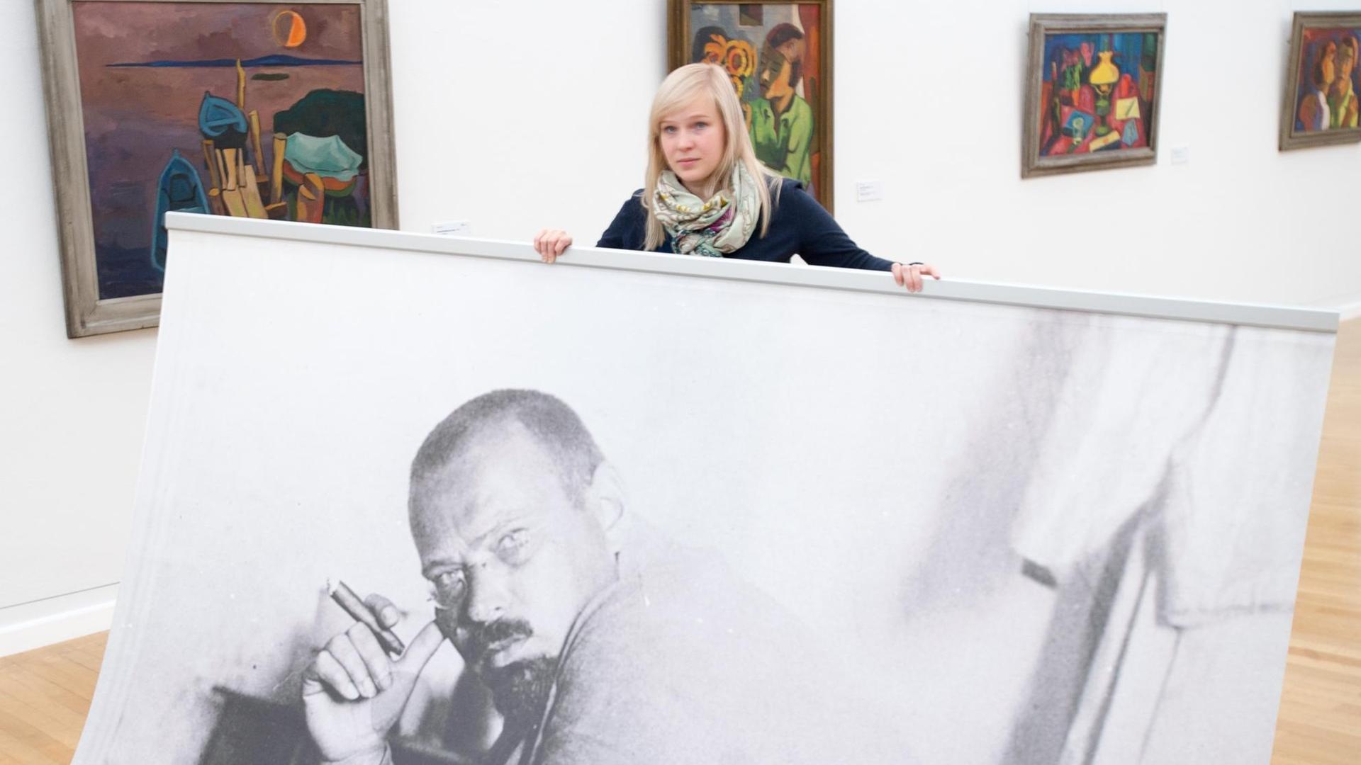 Eine Frau hält ein übergroßes Foto des Künstlers Karl Schmidt-Rottluff (1884-1976) am 11.12.2015 in der Ausstellung "Karl Schmidt-Rottluff - 490 Werke in den Kunstsammlungen Chemnitz" in Chemnitz (Sachsen). Vom 13.12.2015 bis 10.04.2016 werden 490 Arbeiten des Künstlers gezeigt. Eine Frau hält ein übergroßes Foto des Künstlers Karl Schmidt-Rottluff (1884-1976) am 11.12.2015 in der Ausstellung "Karl Schmidt-Rottluff - 490 Werke in den Kunstsammlungen Chemnitz" in Chemnitz (Sachsen). Vom 13.12.2015 bis 10.04.2016 werden 490 Arbeiten des Künstlers gezeigt.