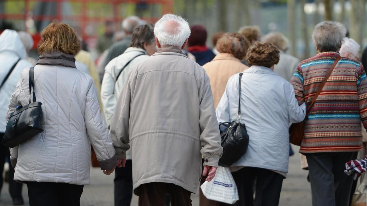 Eine Gruppe Senioren geht am Rheinufer in Mainz spazieren. 