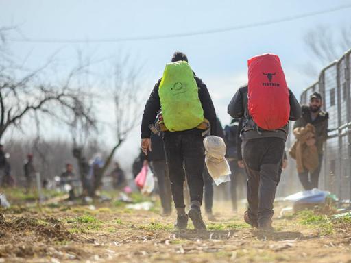 Flüchtlinge sind an einem türkischen Absperrzaun am Grenzübergang Pazarkule-Kastanies in Richtung Griechenland unterwegs.
