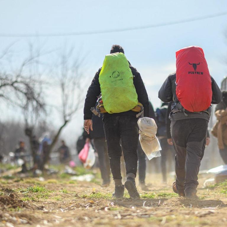 Flüchtling sind an einem türkischen Absperrzaun am Grenzübergang Pazarkule-Kastanies in Richtung Griechenland unterwegs. 